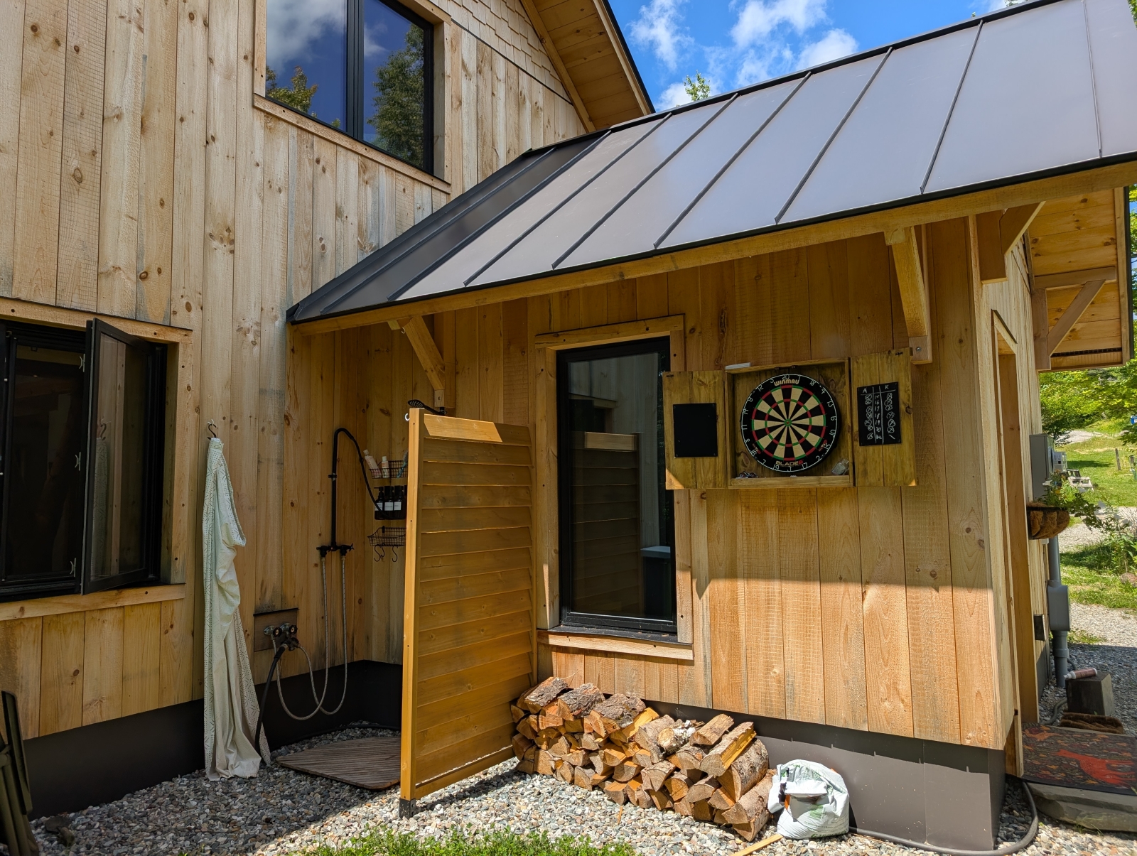 Outdoor shower, firewood, and dartboard.