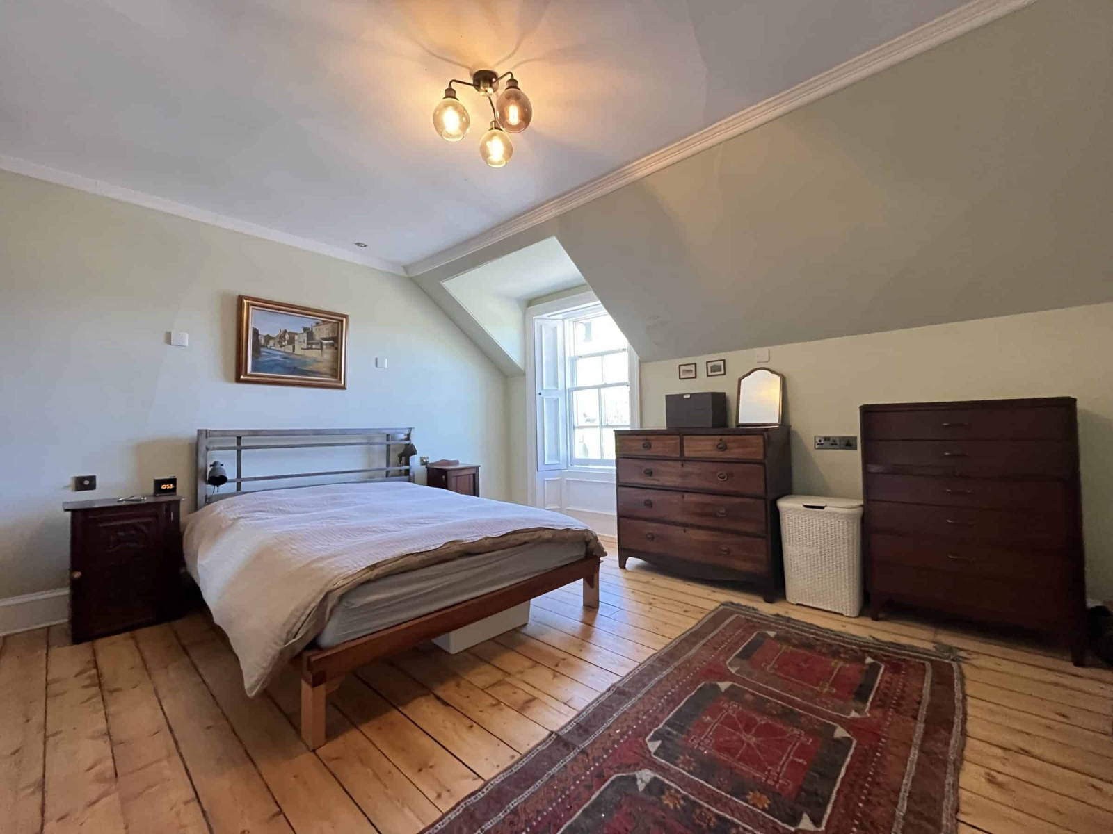 Quarto principal espaçoso no último andar da casa da cidade. Cama king size, com duas mesinhas de ca ...