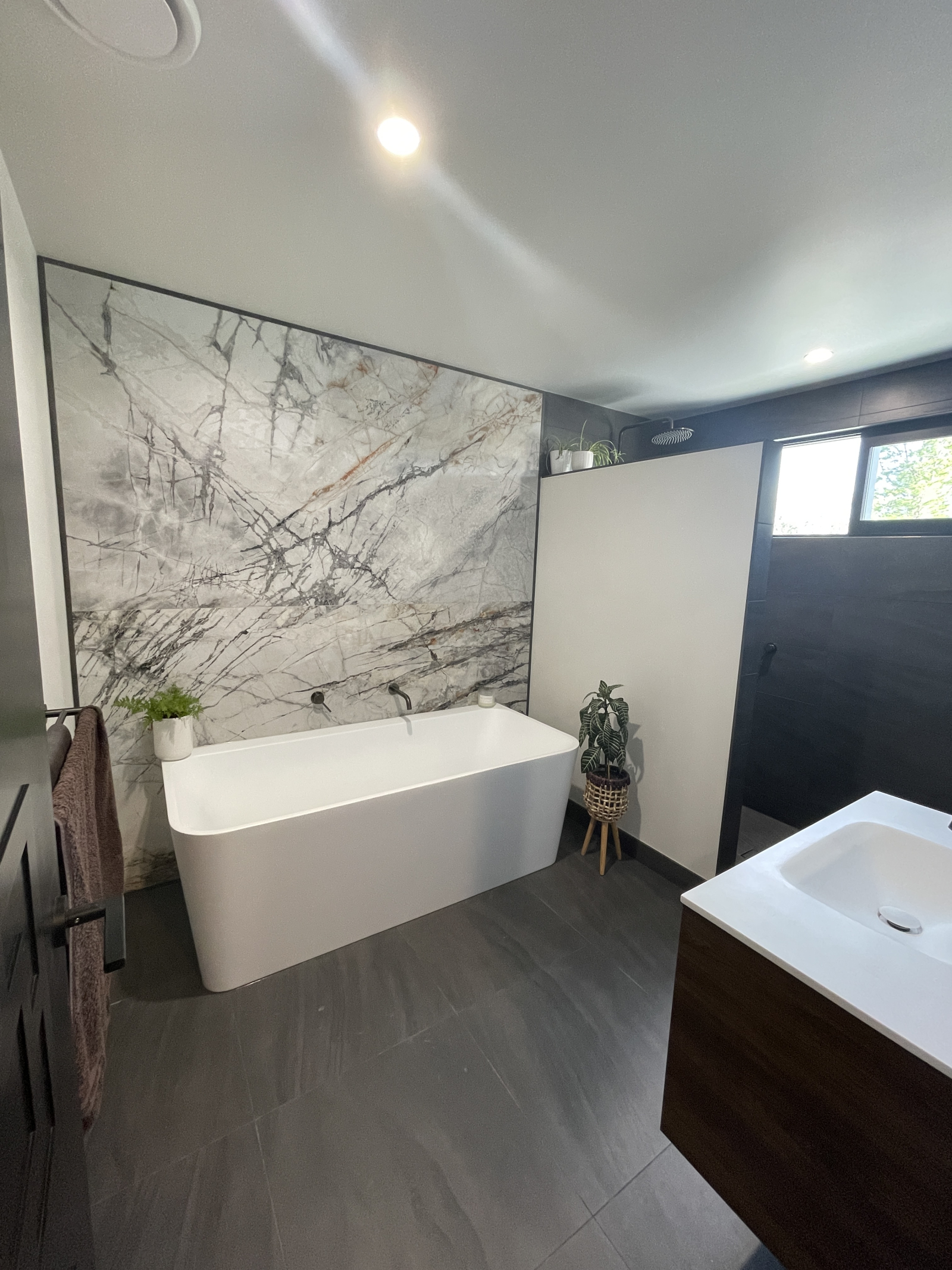 Das Hauptbadezimmer mit großer, tiefer Badewanne, LED-Spiegel, Fußbodenheizung und ebenerdiger Dusch ...