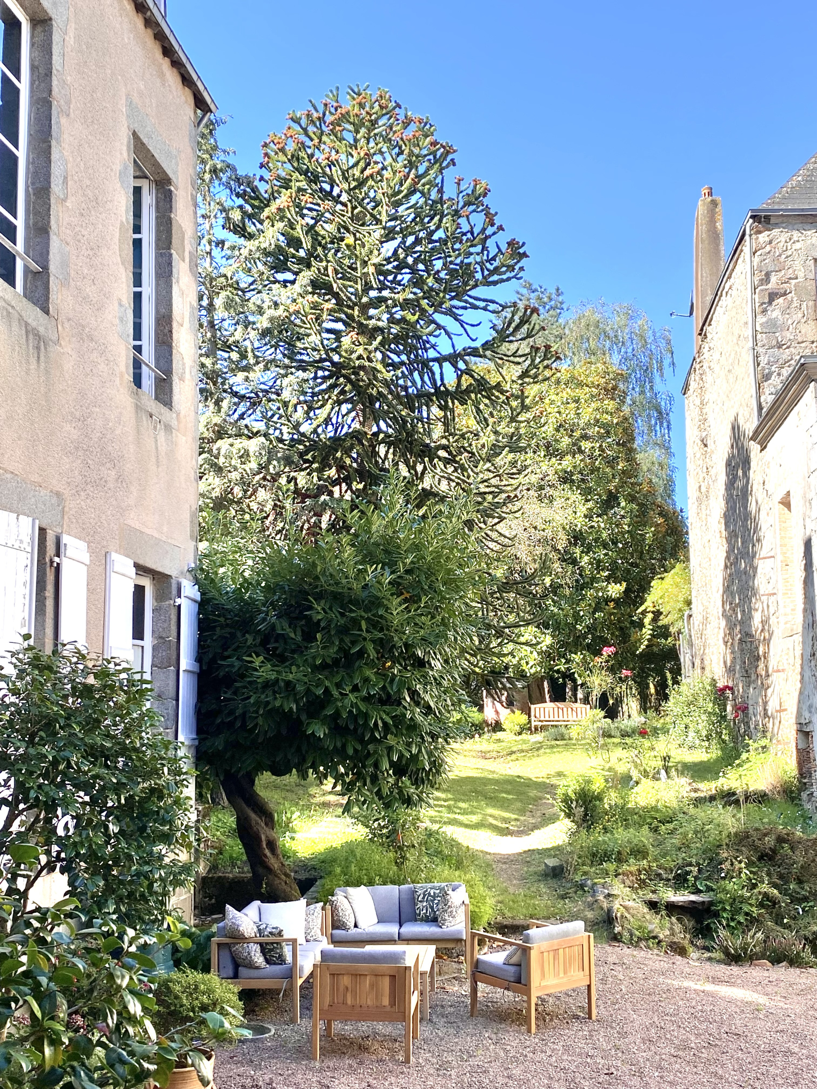 A casa está voltada internamente para um jardim de rosas no pátio, com assentos ao ar livre, com um ...