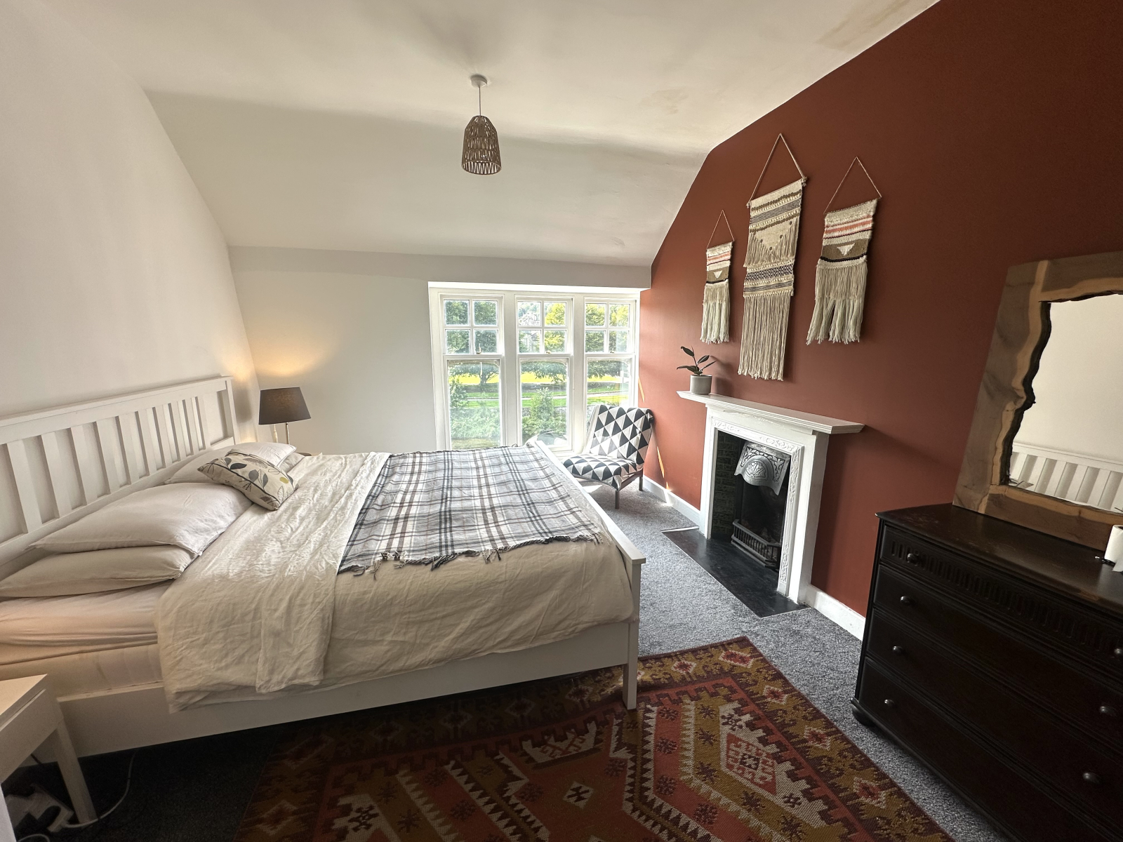 Grande quarto principal com cama king size e janelas duplas voltadas para o rio e a floresta.