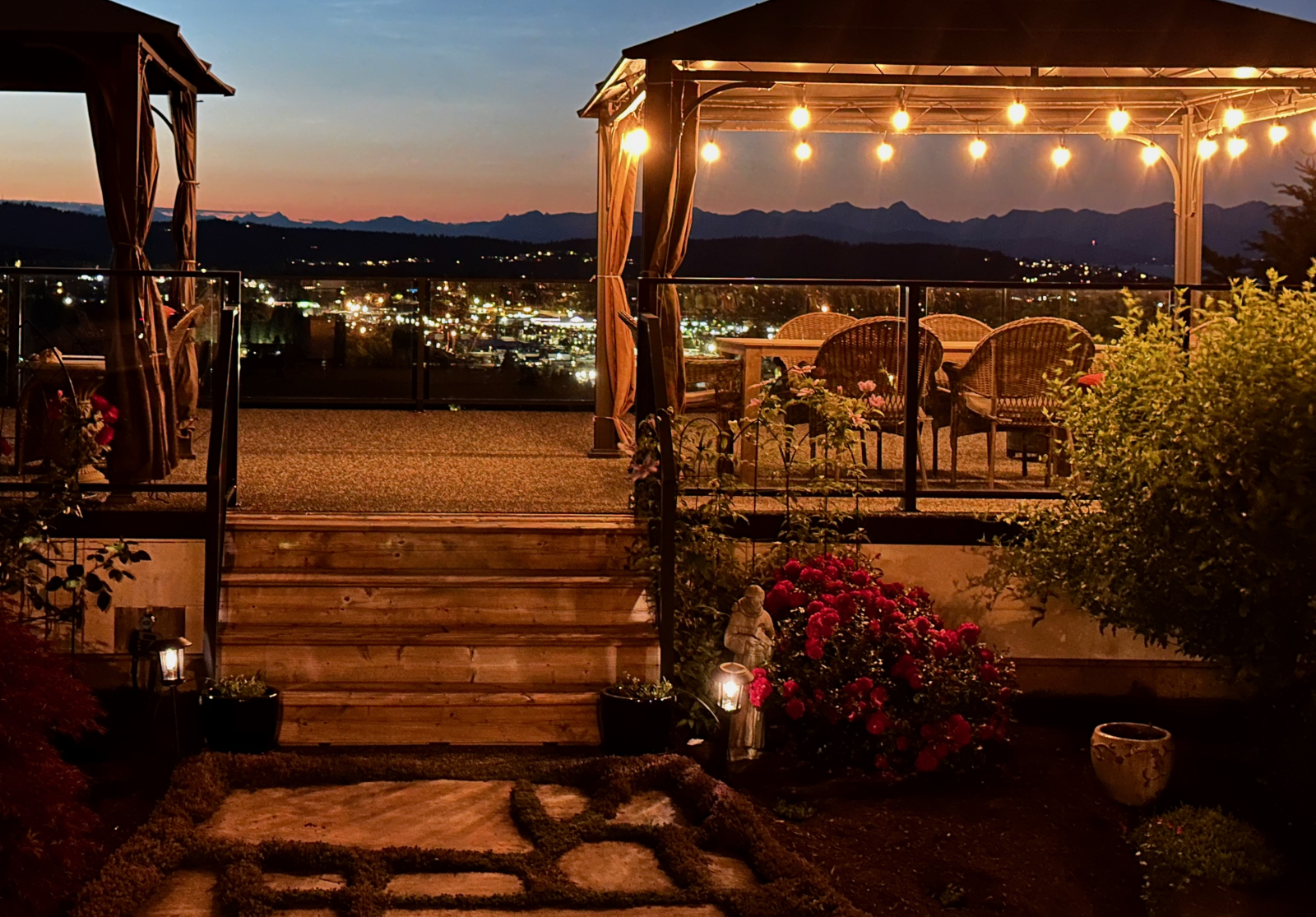 Vista crepuscolare dal ponte con luci della città e montagne lontane.