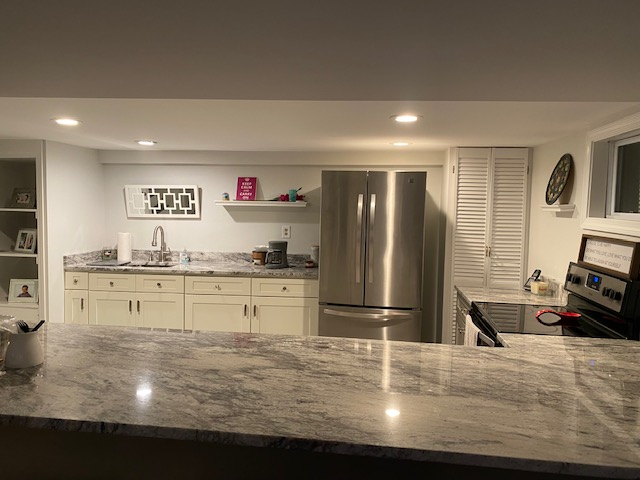 Kitchen with 4 bar stools and 1/2 bathroom off this to the left.