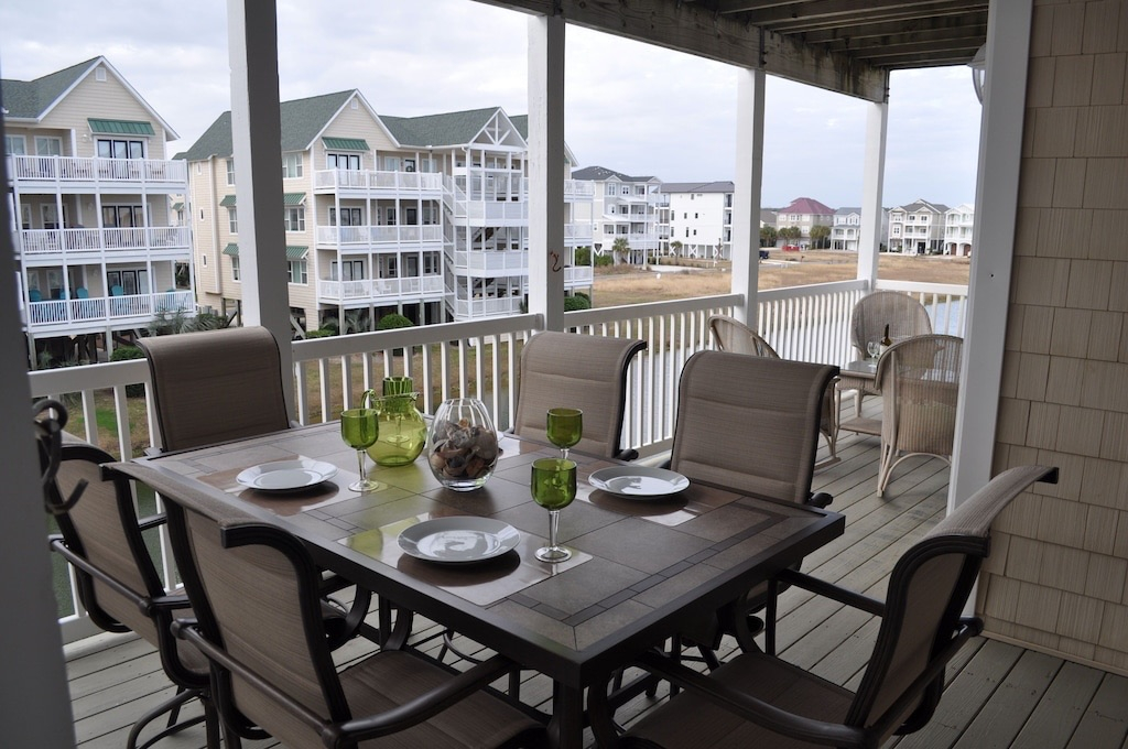 Large table on porch that seats six, perfect for enjoying meals outside.