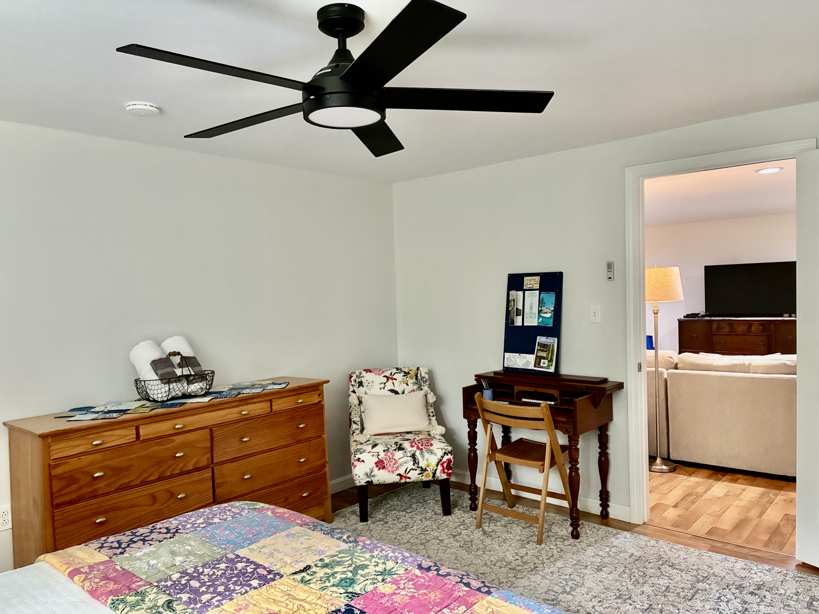 Guest bedroom  has a bureau, small sitting chair, and writing desk.