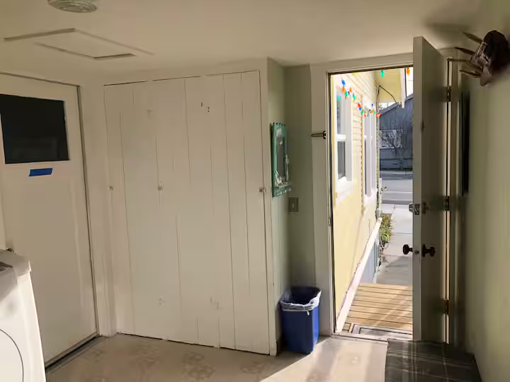 Entrada lateral con acceso a la despensa de alimentos, lavadora y secadora, y la cocina.