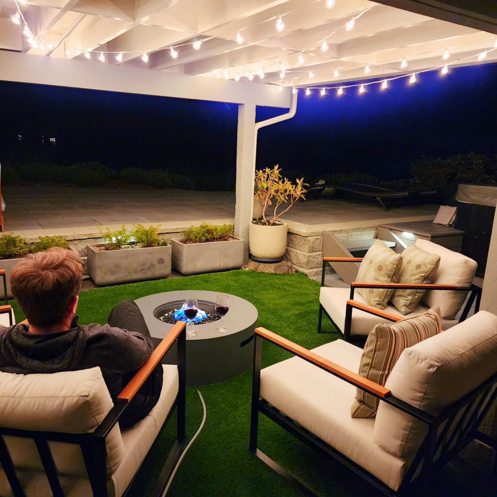 Le coin salon couvert au-delà de la rocaille comprend des chaises confortables et un foyer.