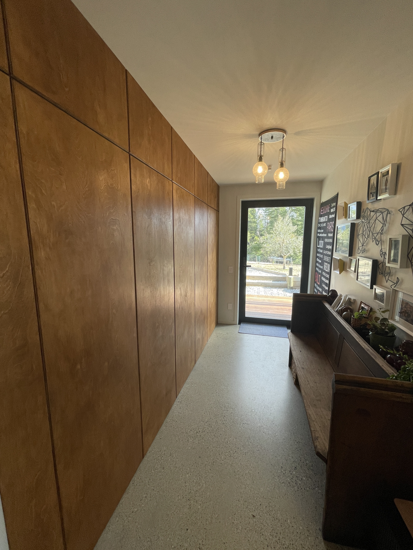 Der Haupteingang mit einer Foto-Reisewand, einer 120-jährigen Kirchenbank aus dem Land Victoria, Aus ...