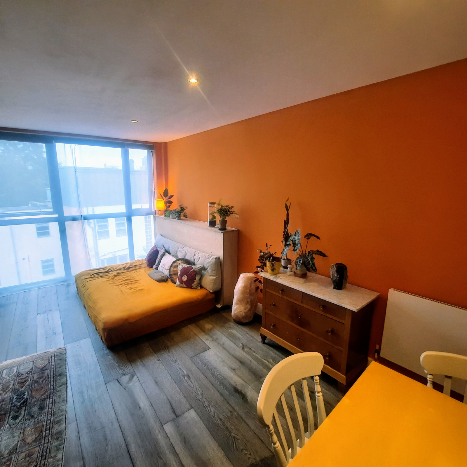 Sala de estar em plano aberto ensolarado. Mesa de jantar para 4-6 pessoas.