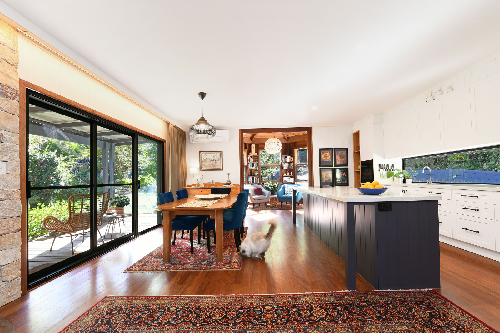 Cuisine ouverte, salle à manger avec table pour 6 personnes et coin bibliothèque