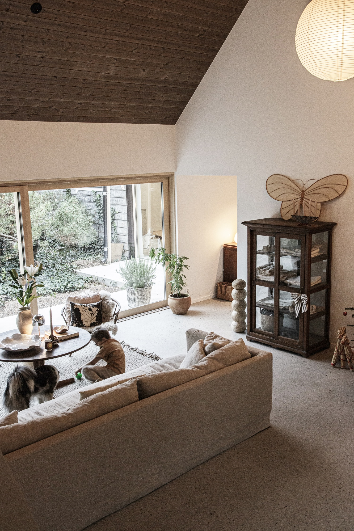 Dies ist unser Wohnzimmer mit einem hohen Dach und großen Terrassenfenstern und -türen, um das Gefüh ...