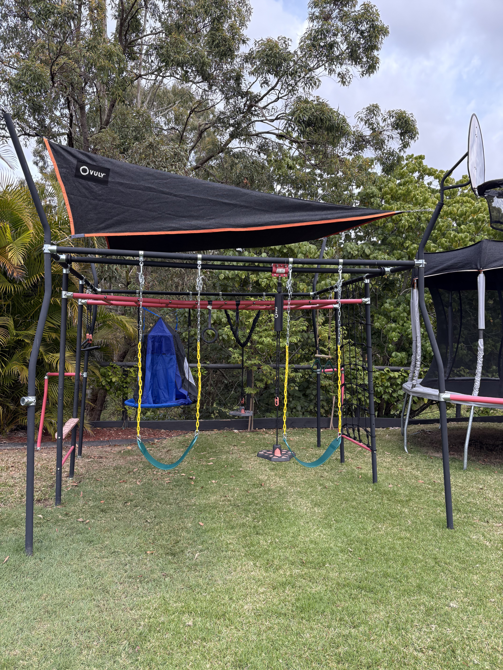Large trampoline, monkey bars and swing set in the yard.