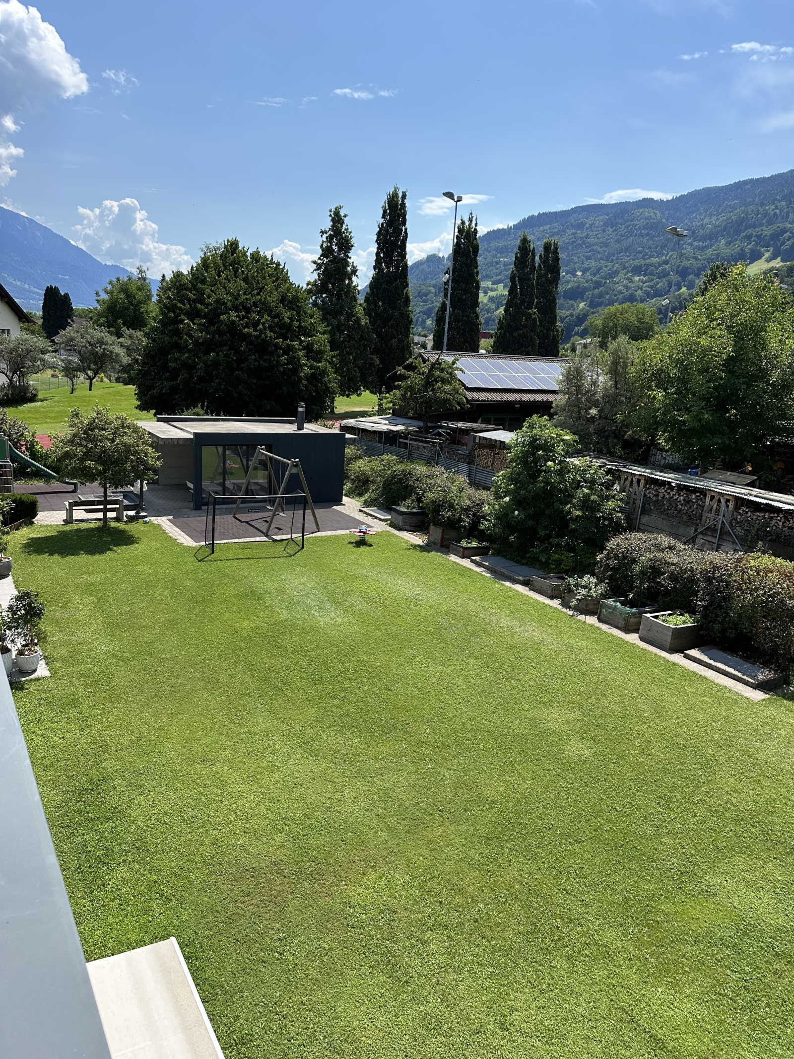 Patio trasero compartido con área de juegos infantiles y parrilla