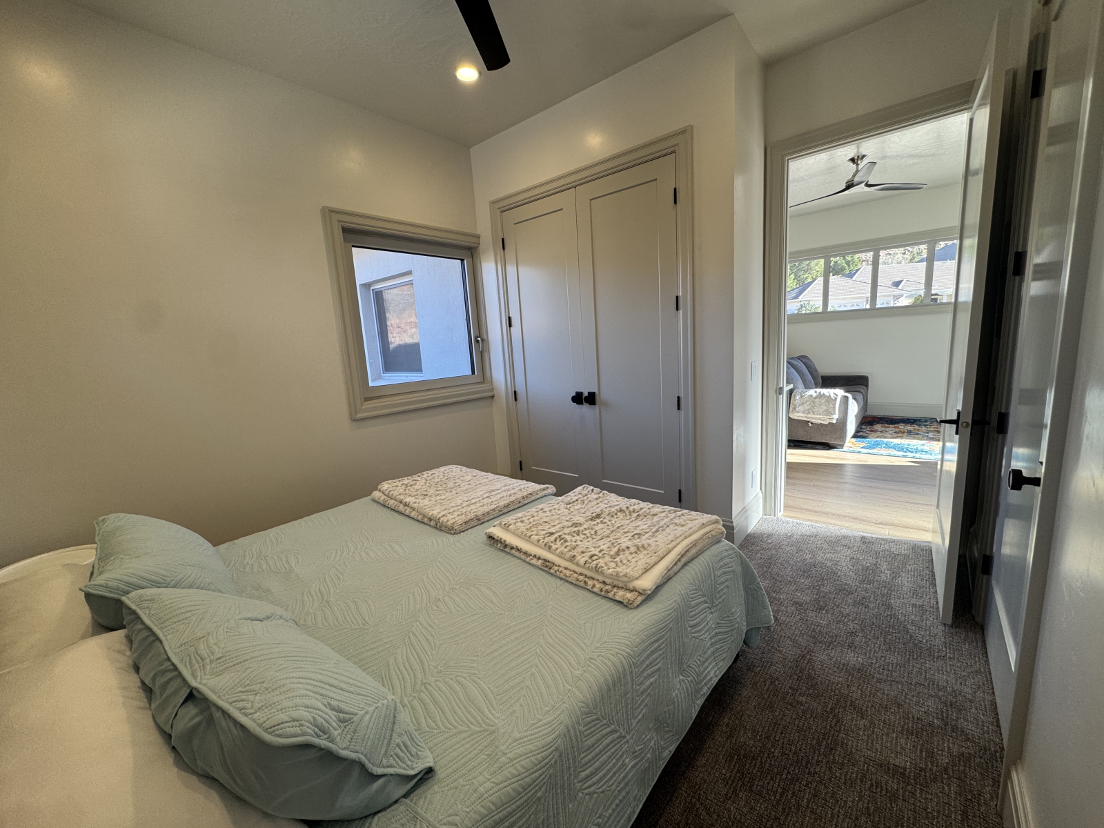 Chambre de gauche avec des placards à double porte au pied du lit, porte de salle de bain à droite.